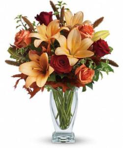 peach colored lilies and red roses with green accents in vase