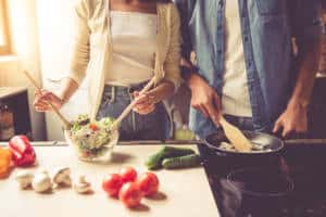 Couple making salad side by side in the kitchen