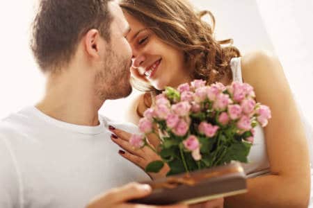 Picture showing man giving flowers and present to woman in bed
